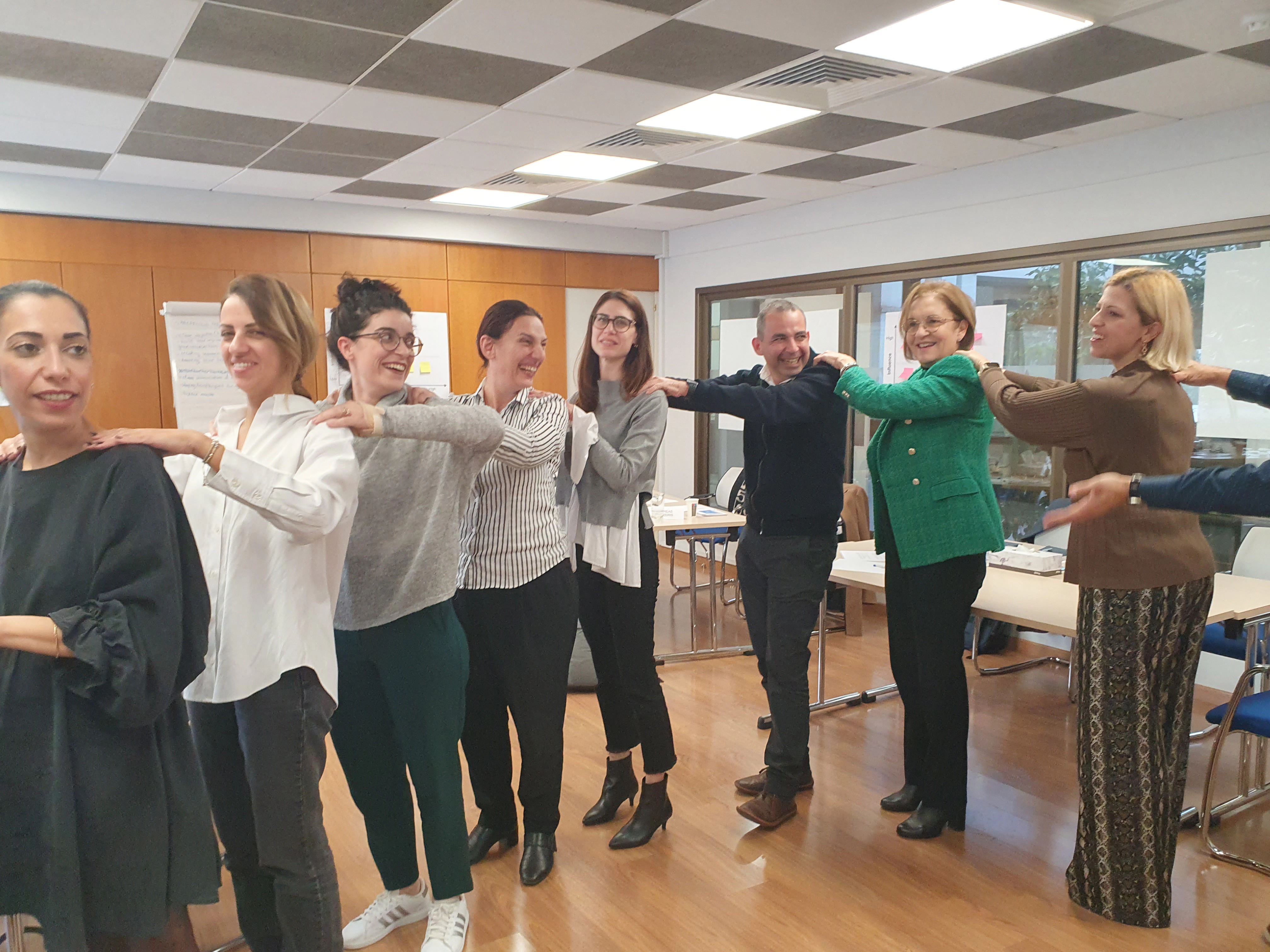 Team building during negotiation training — participants smiling and supporting each other in a line.