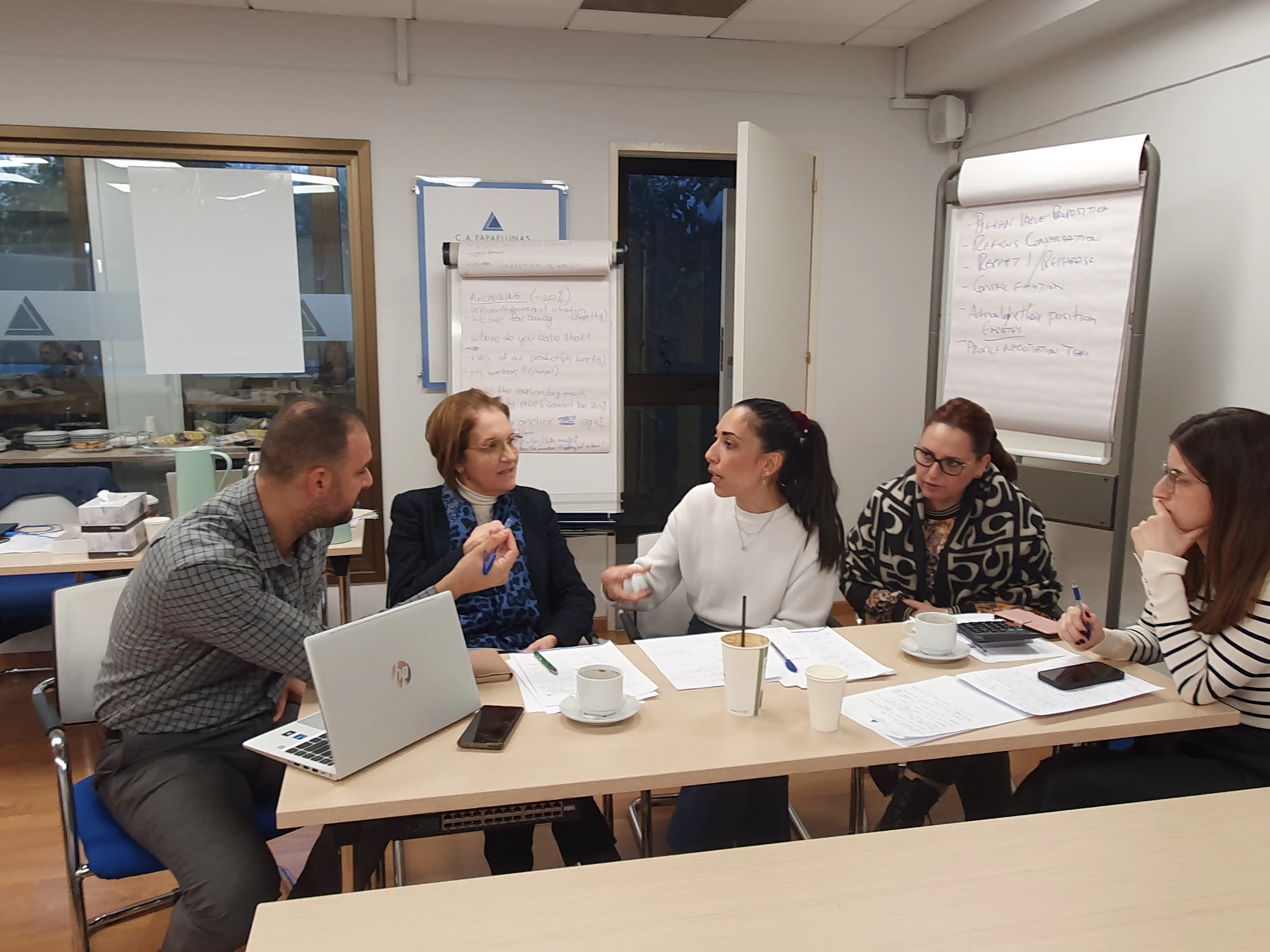 Participants engaged in a negotiation exercise as one team member confidently presents their viewpoint.