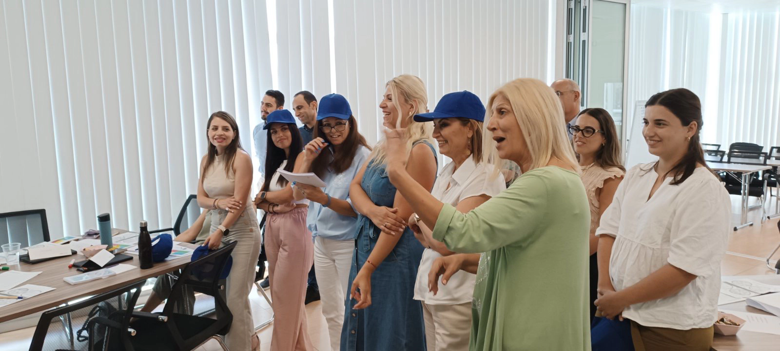 Professionals participating in an interactive seminar exercise, standing and engaging in discussion as a woman speaks to the workshop facilitator.