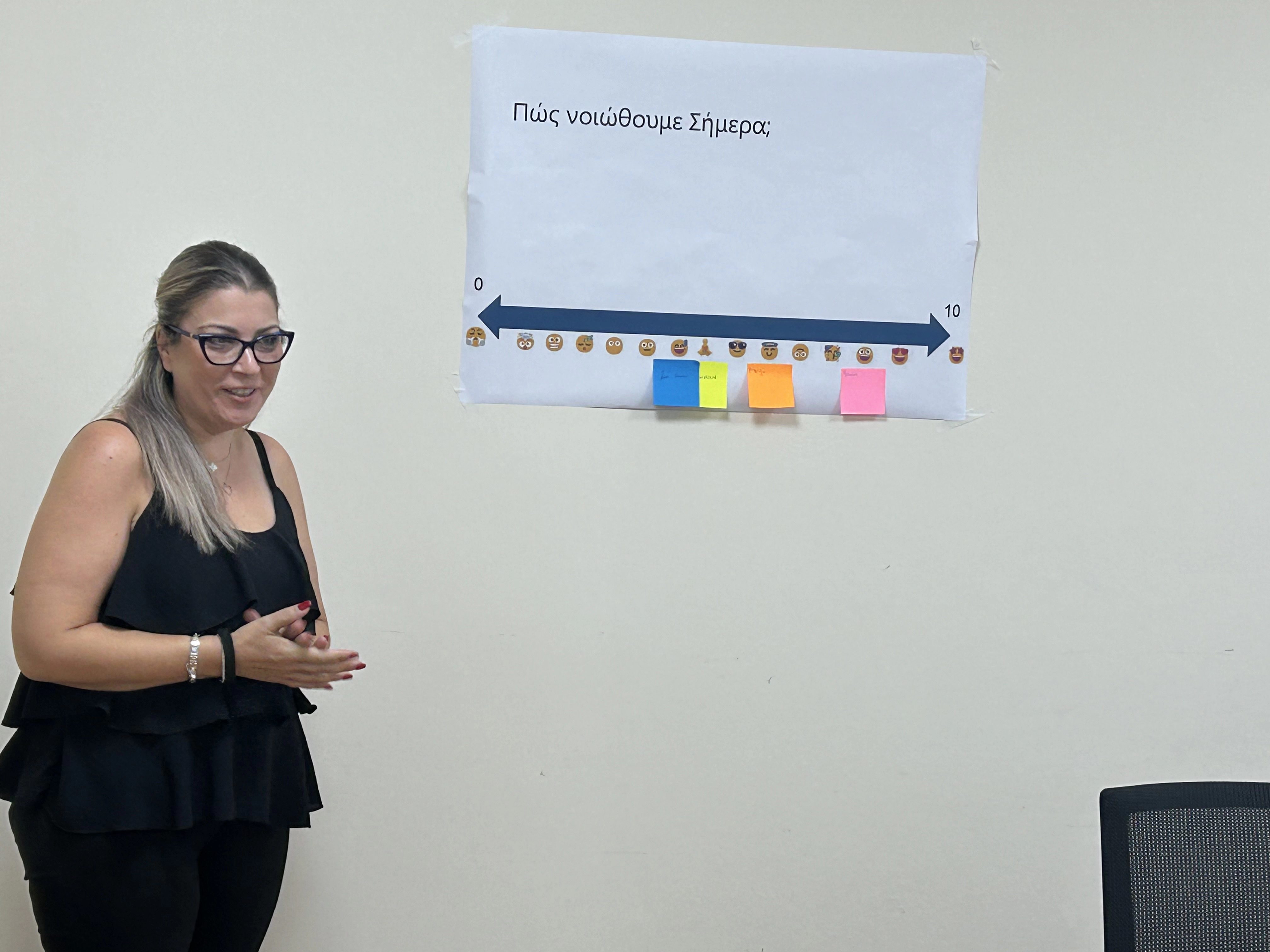 Professional woman standing by a wall with paper and sticky notes capturing participants’ feelings during the seminar.