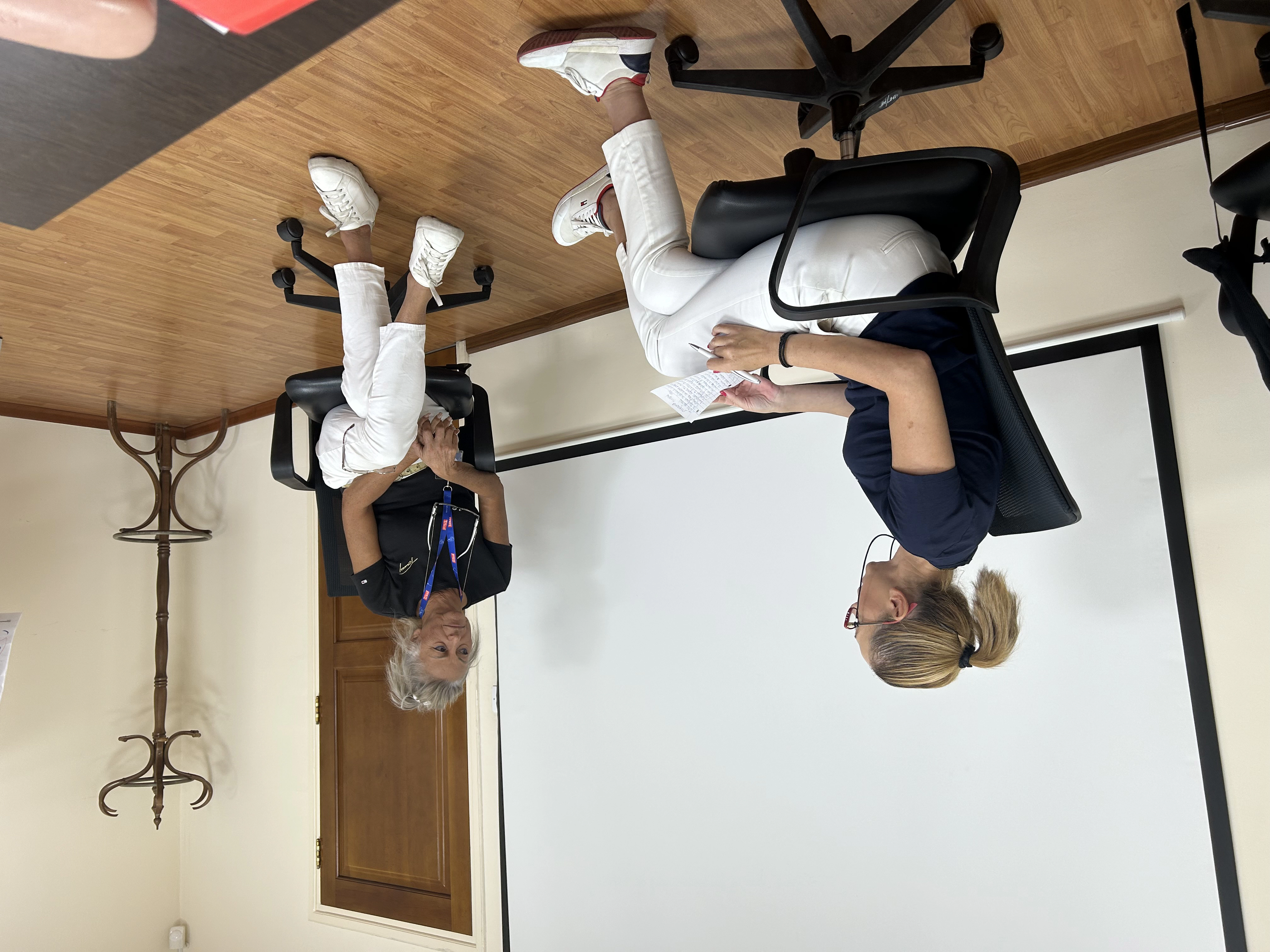Two professional women seated on office chairs, engaging in an interactive dialogue during the workshop.